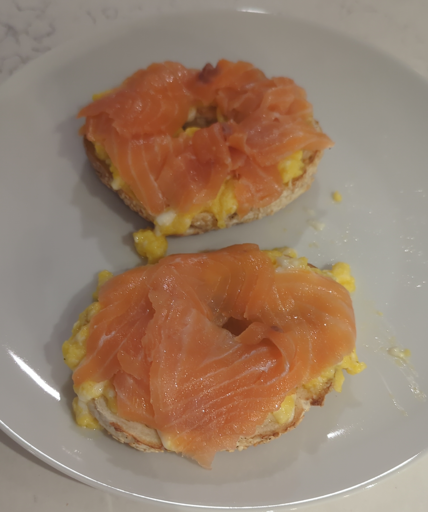 A bagel topped with scrambled eggs and smoked salmon